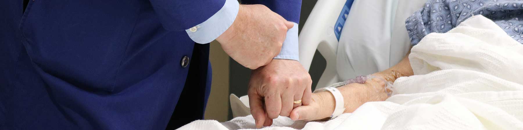 Chaplain holding the hand of a patient