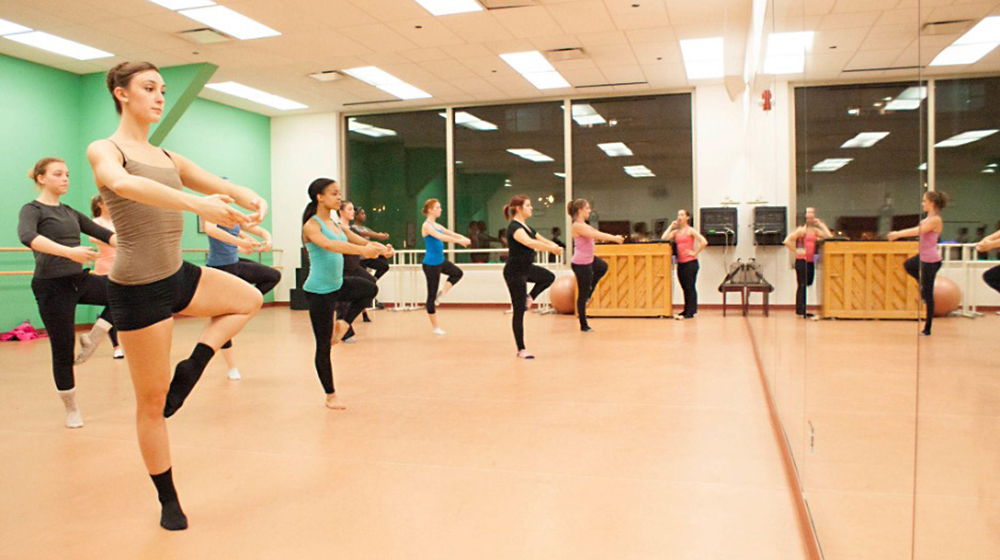 A small group of dance students practice in the studio as an instructor leads the class.