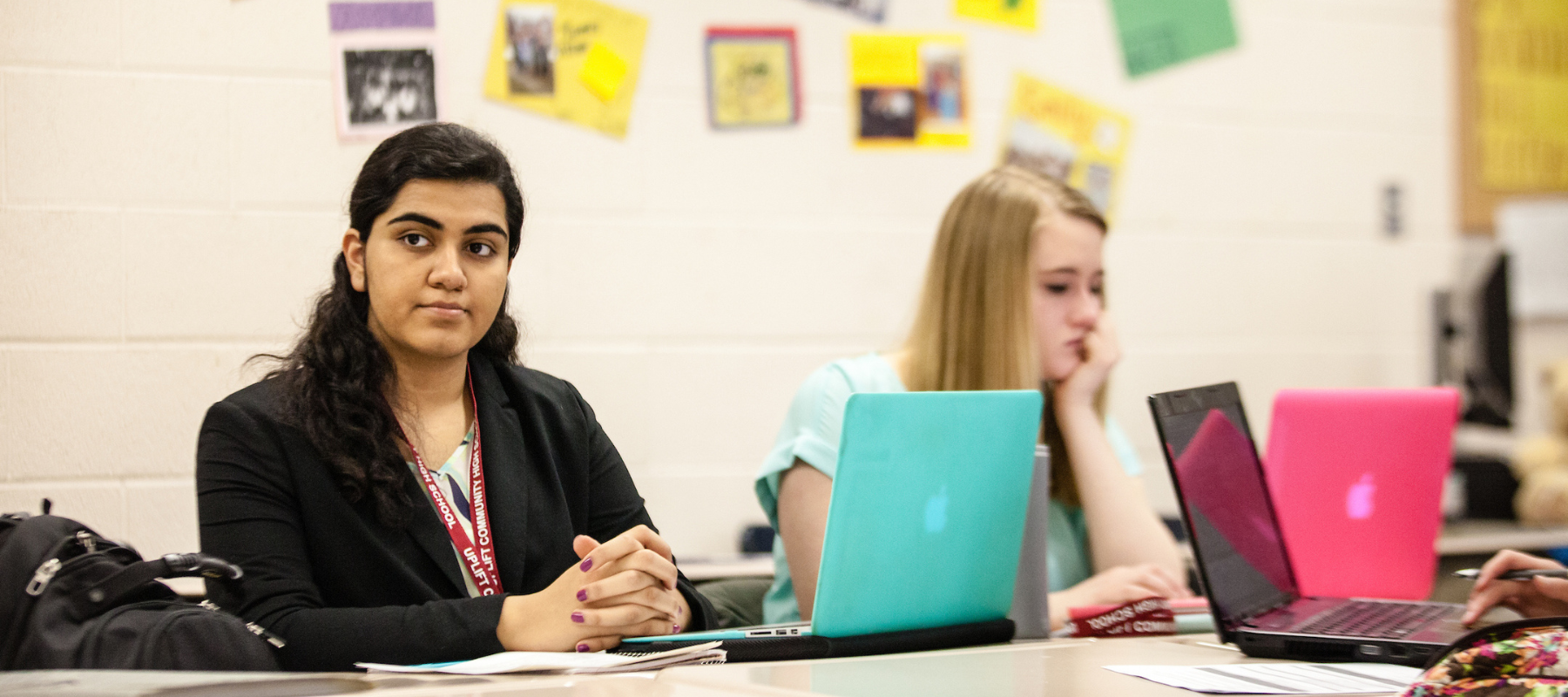 Armeen Saying sitting at a desk with her computer in class