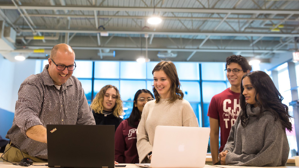 An engineering professor interacts with three attentive students