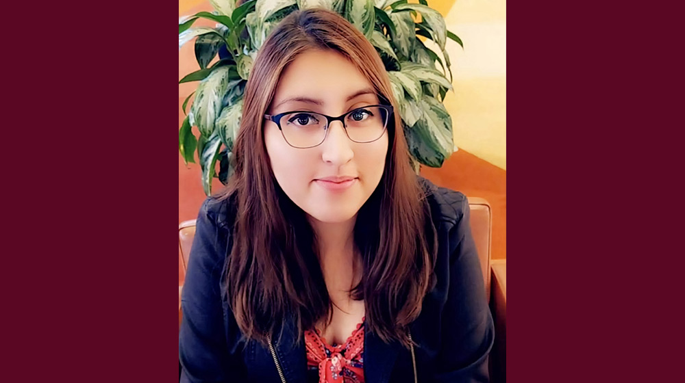 Headshot of a brunette person with glasses