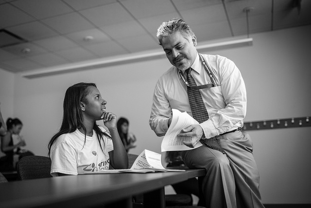 Dr. Rene Luis Alvarez works with a student during a break from his Western Civilization to 17th Century class on Arrupe College's opening day last August.