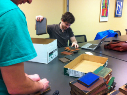 Evan Thompson looks on as Zac Davis unpacks a box of books.