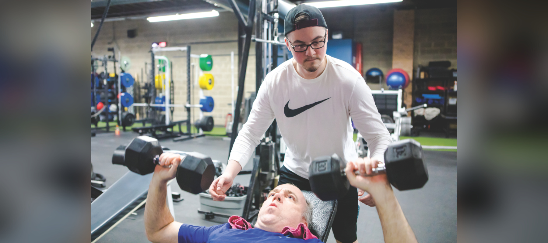 Trainer helping client lift weights.